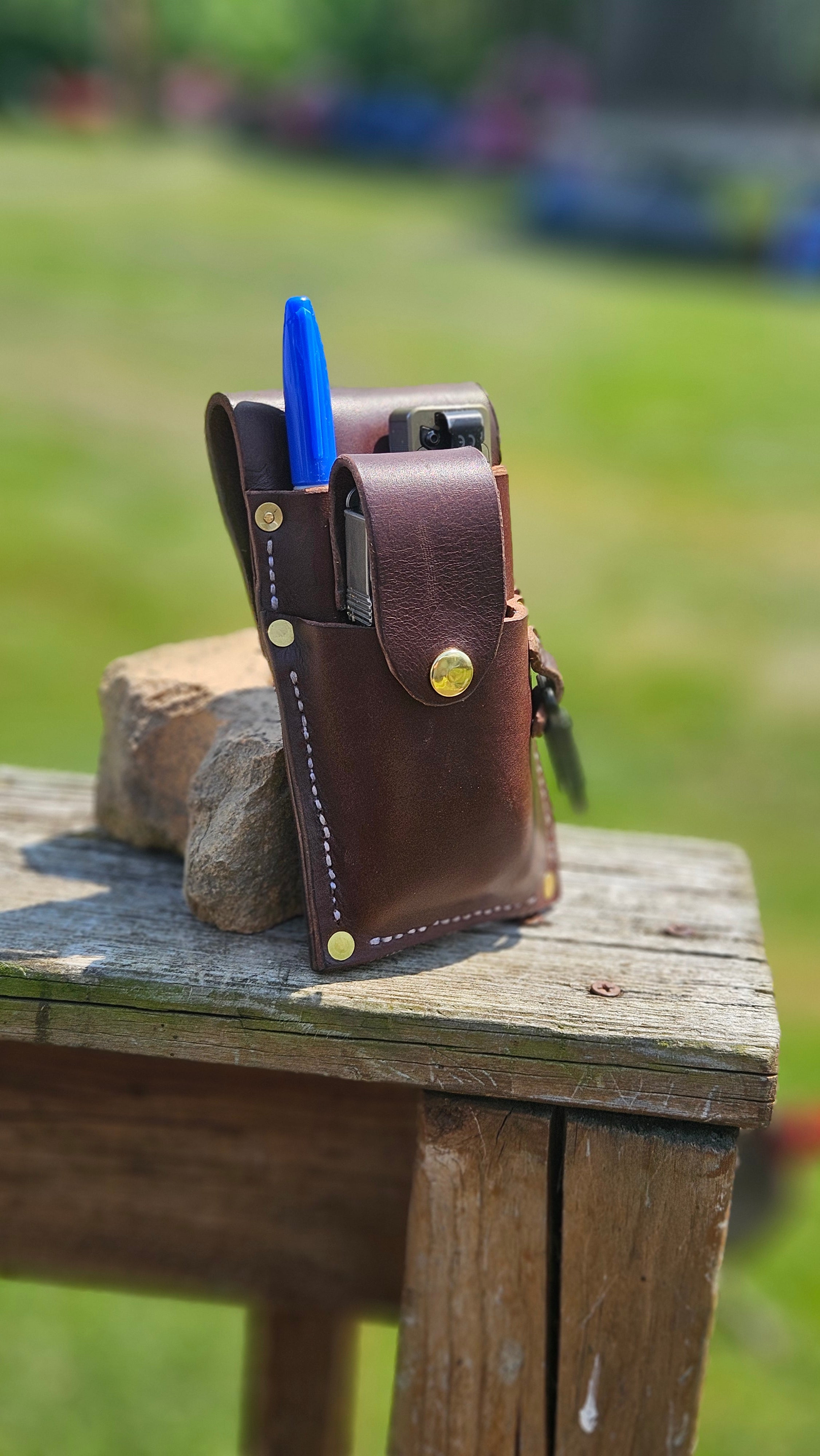 Brown leather wallet with blue pen on a wooden surface